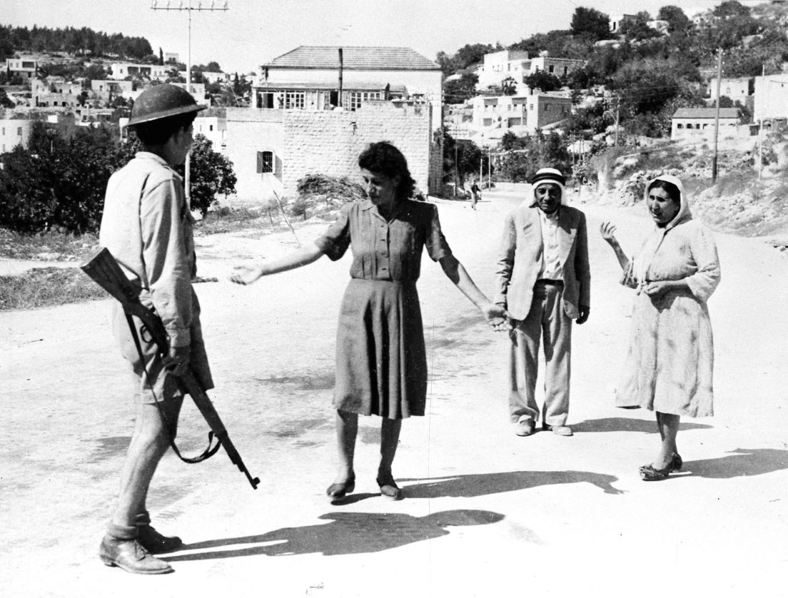 An Israeli soldier stops Palestinians in Nazareth, 1948, for traveling after the imposed curfew